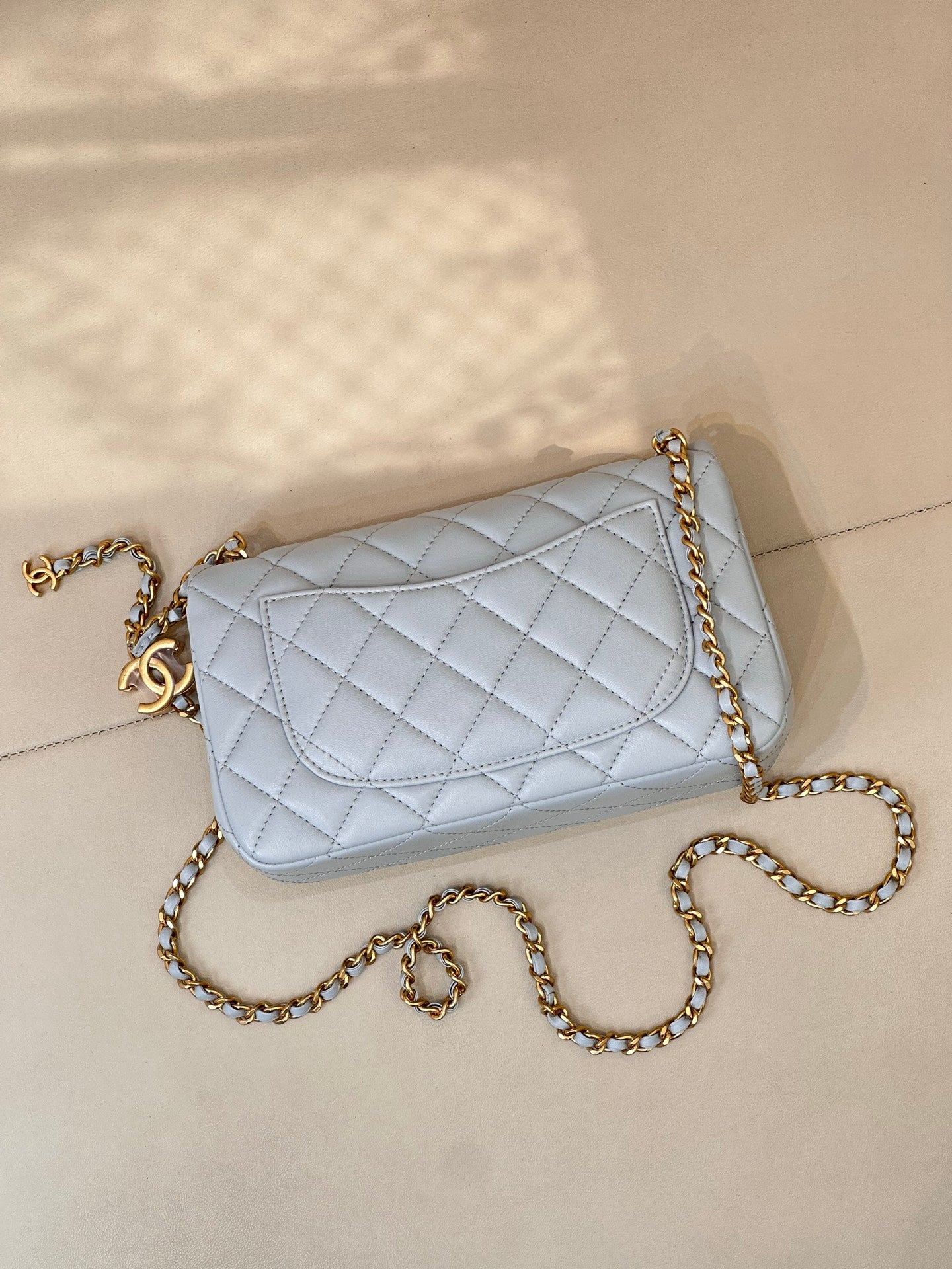 Light blue quilted flap crossbody bag with gold chain and gold logo on front