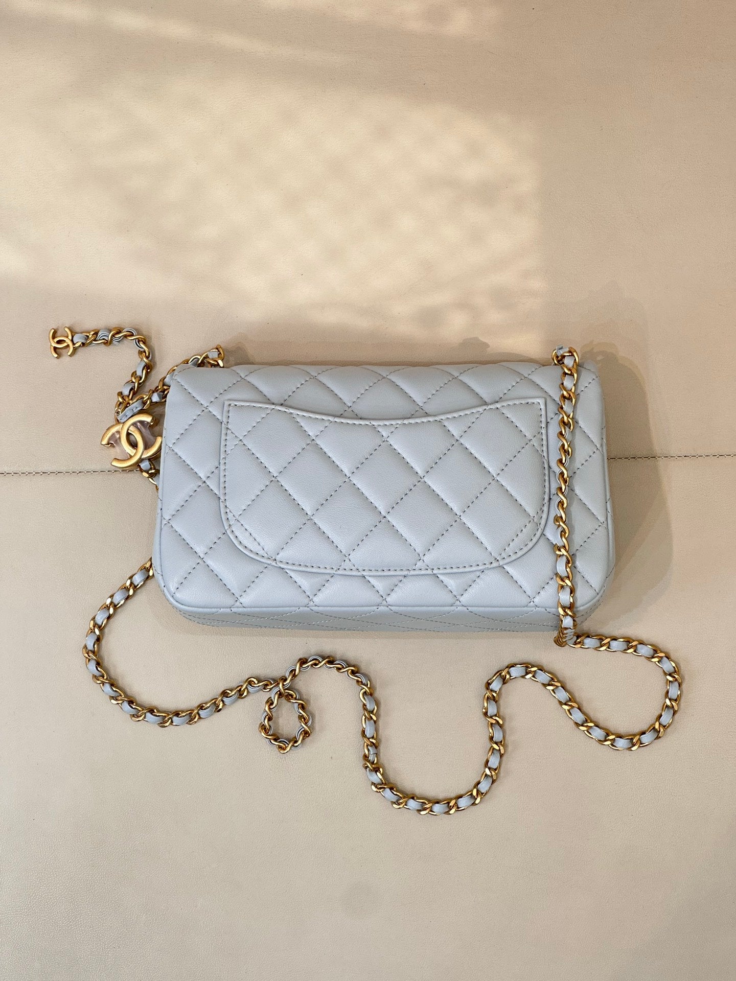 Light blue quilted flap shoulder bag with gold chain strap and gold logo hardware