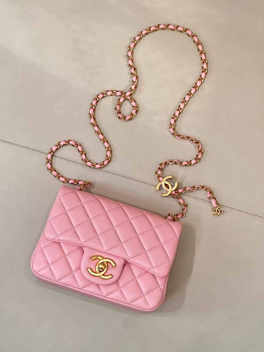 Pink quilted Chanel mini flap bag with gold-tone logo and chain shoulder strap