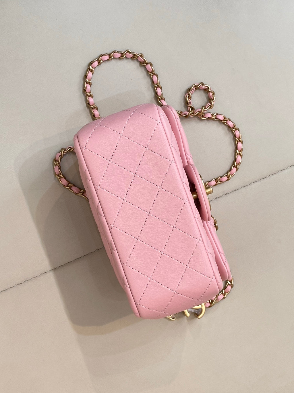 Pink quilted Chanel mini bag with gold-tone chain crossbody strap, side view