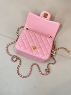 Pink quilted Chanel mini bag with top handle and chain strap, gold-tone logo