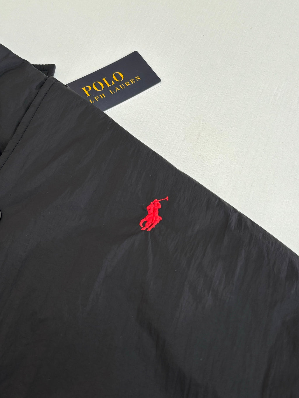 Red polo pony logo on black jacket chest area
