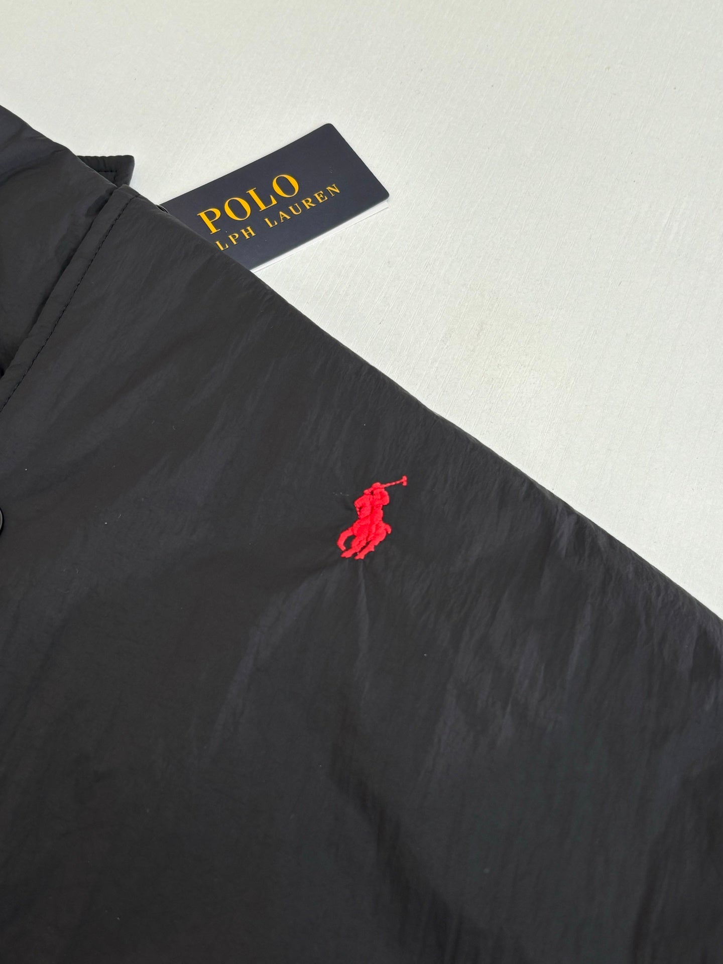 Red polo pony logo on black jacket chest area