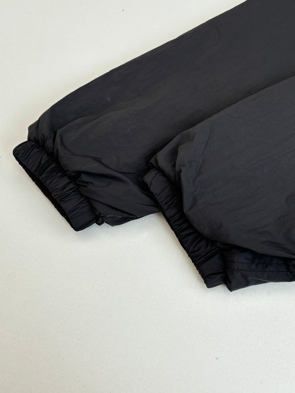 Black puffer jacket sleeve and hem with gathered stitching