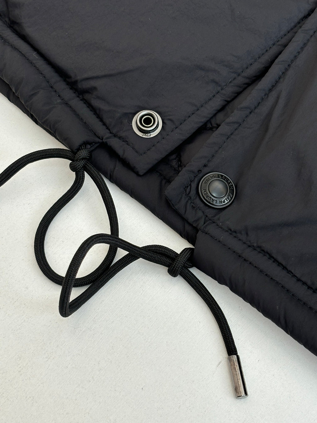 Black jacket with drawstring waist and metal snap/button details