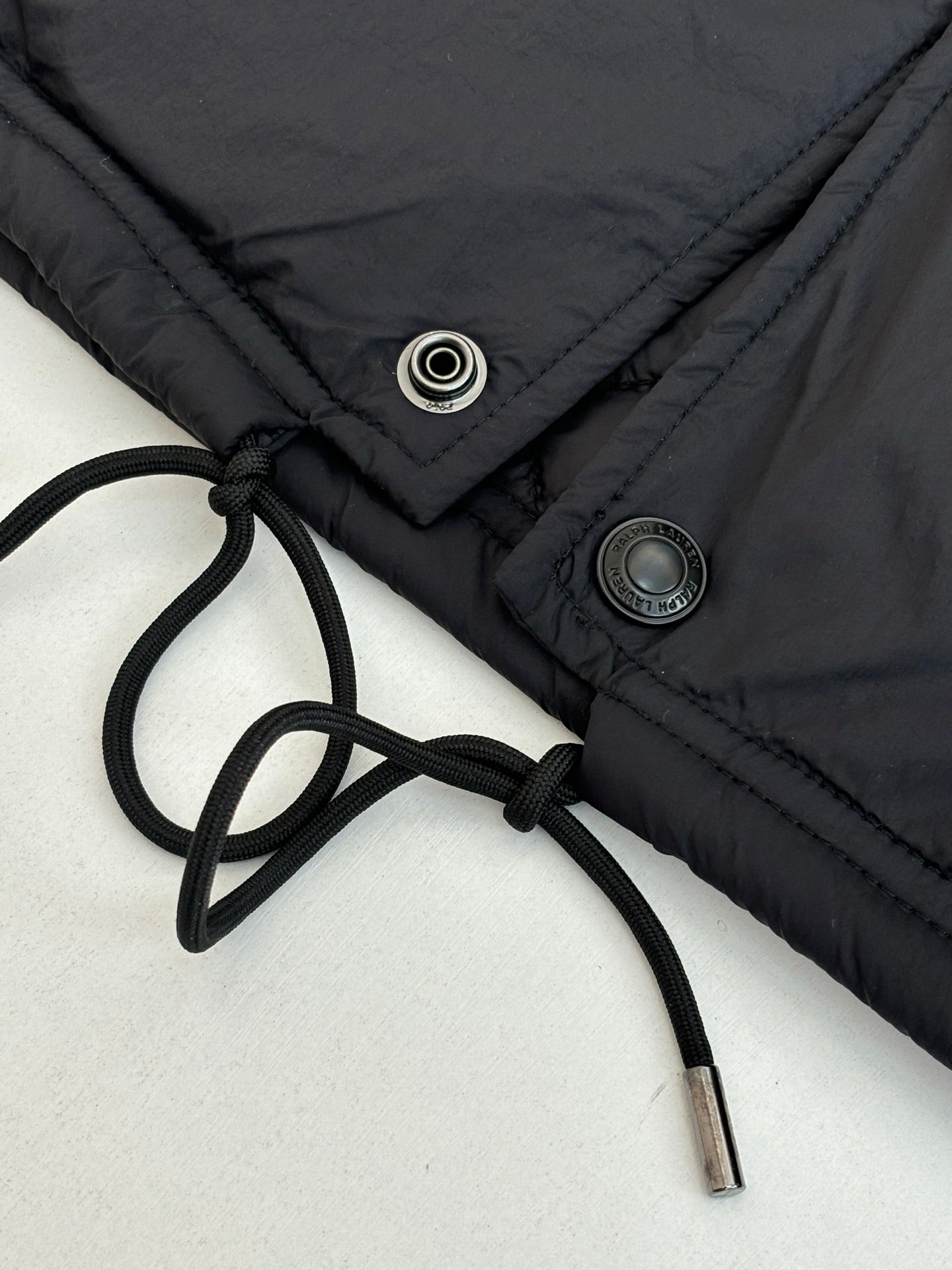 Black jacket with drawstring waist and metal snap/button details