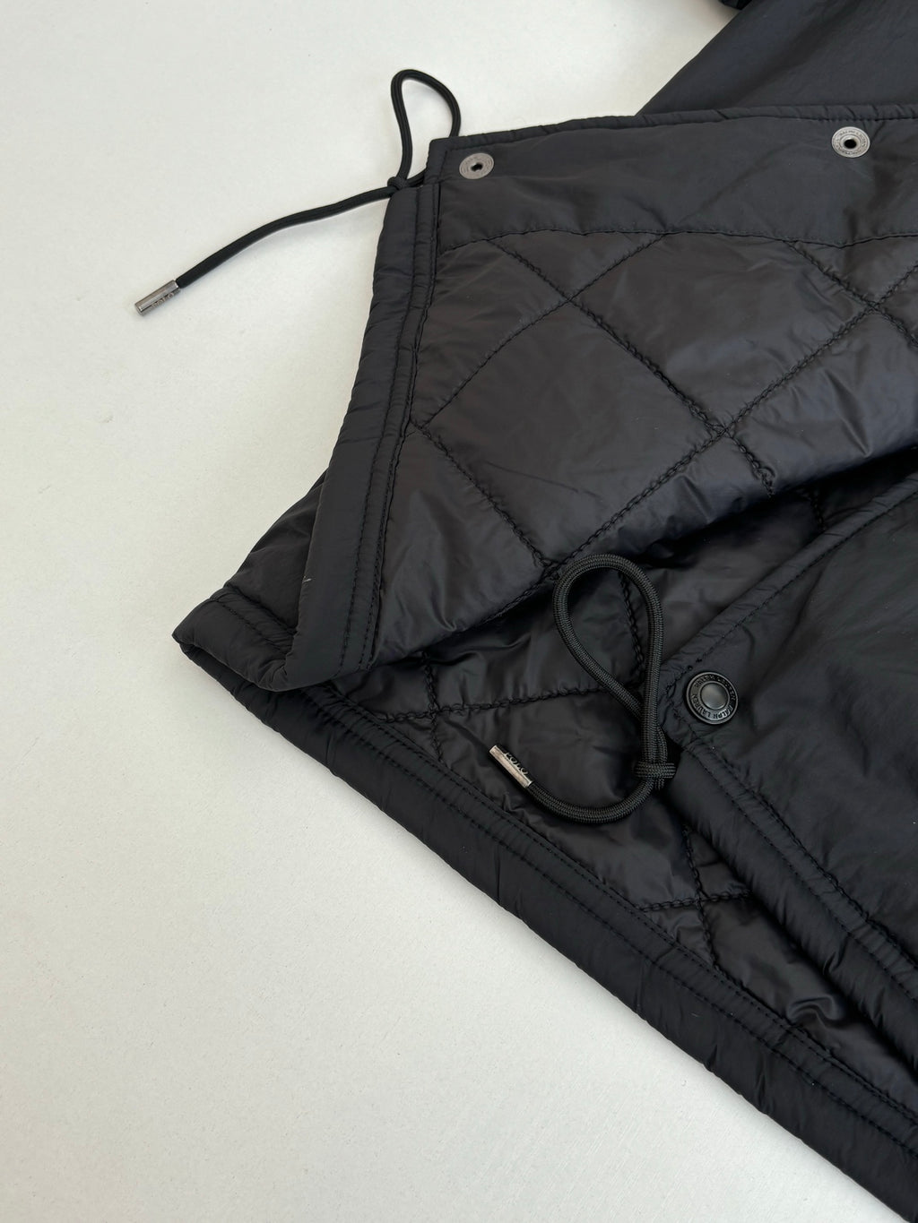 Black jacket with drawstring ties and metal button hardware