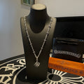 Silver chain necklace with square pendant on black display bust