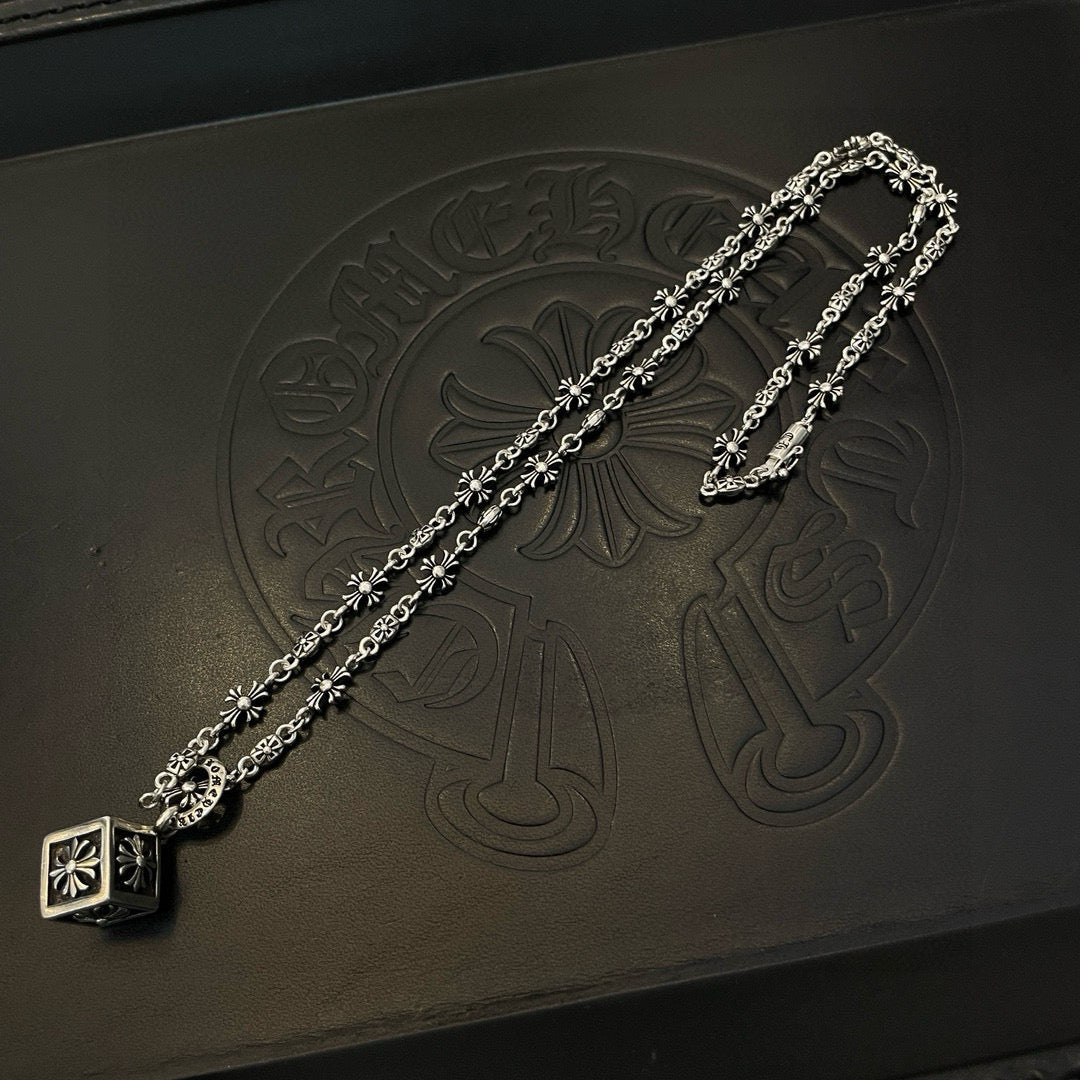 Silver floral chain necklace with square pendant on black accessory box