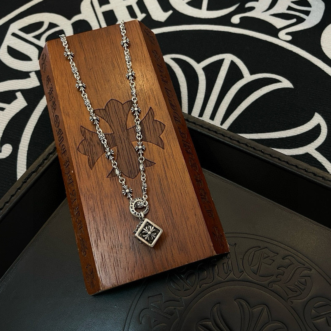 Silver chain necklace with square pendant on wooden jewelry card over black box