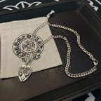 Silver-tone chain necklace with Chrome Hearts heart pendant beside a cloth pouch