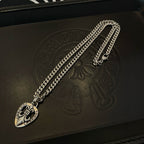 Silver-tone necklace chain with Chrome Hearts heart pendant on a black case lid