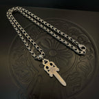 Silver-tone chain necklace with dagger charm pendant on embossed mat