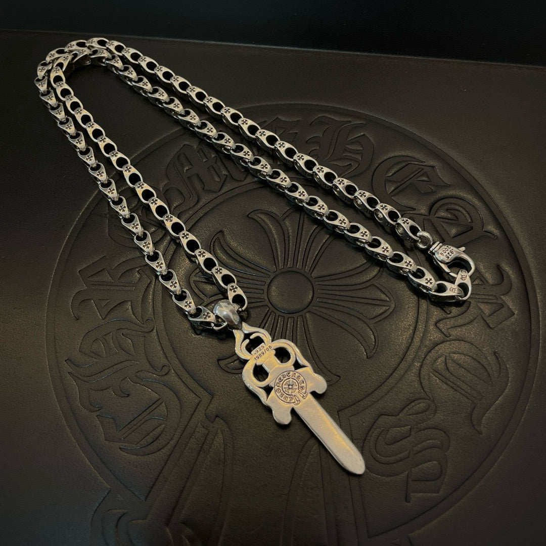 Silver-tone chain necklace with dagger charm pendant on embossed mat