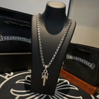 Silver-tone chain necklace with crown-and-cross charm and layered links
