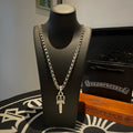 Silver-tone chain necklace with cross pendant on dark display bust