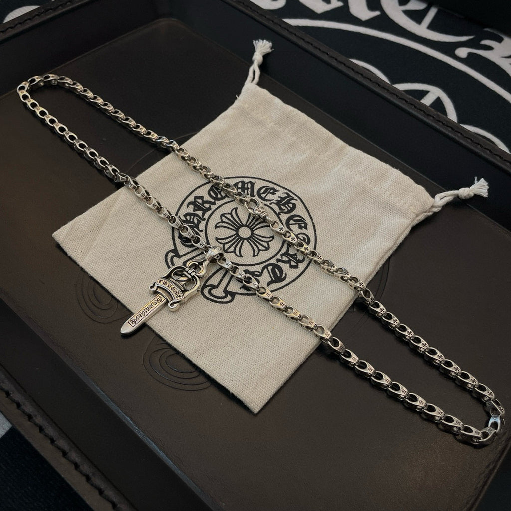 Silver-tone chain necklace with cross dagger pendant on drawstring pouch