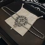 Silver-tone chain necklace with cross dagger pendant on drawstring pouch