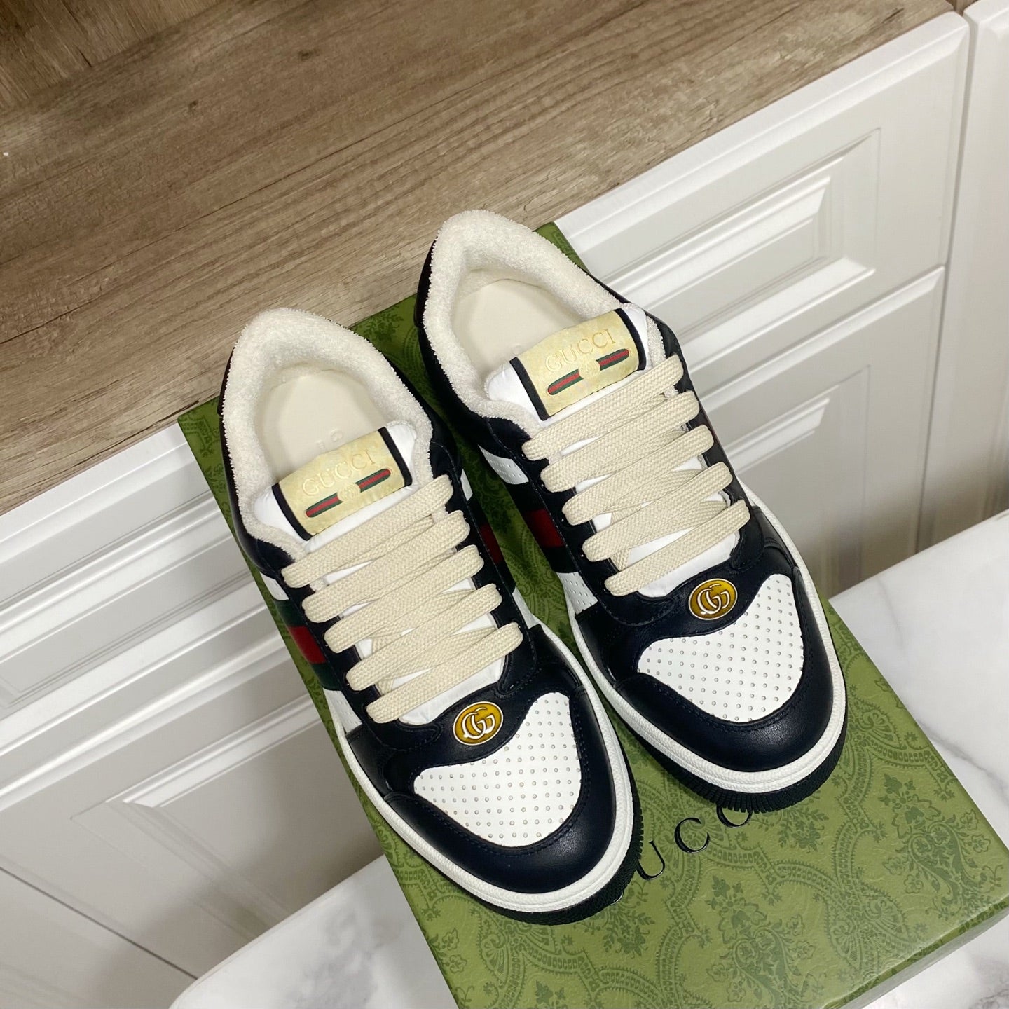 Gucci unisex sneakers with cream laces, navy leather, and green/red web stripe detail