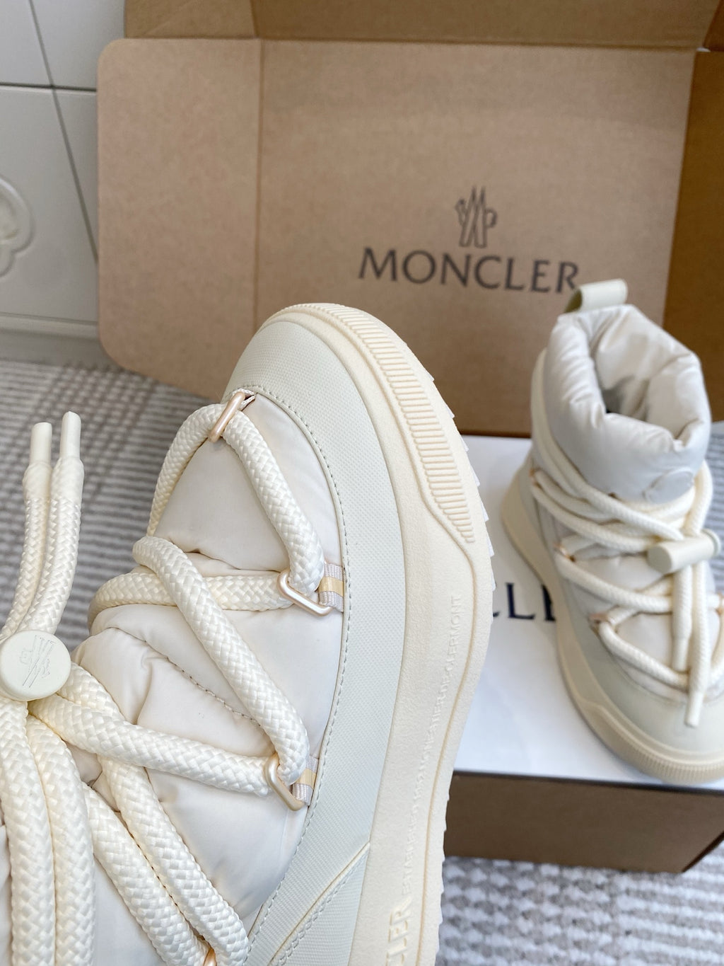 White Moncler high-top sneaker side view with lace-up stitching and thick sole