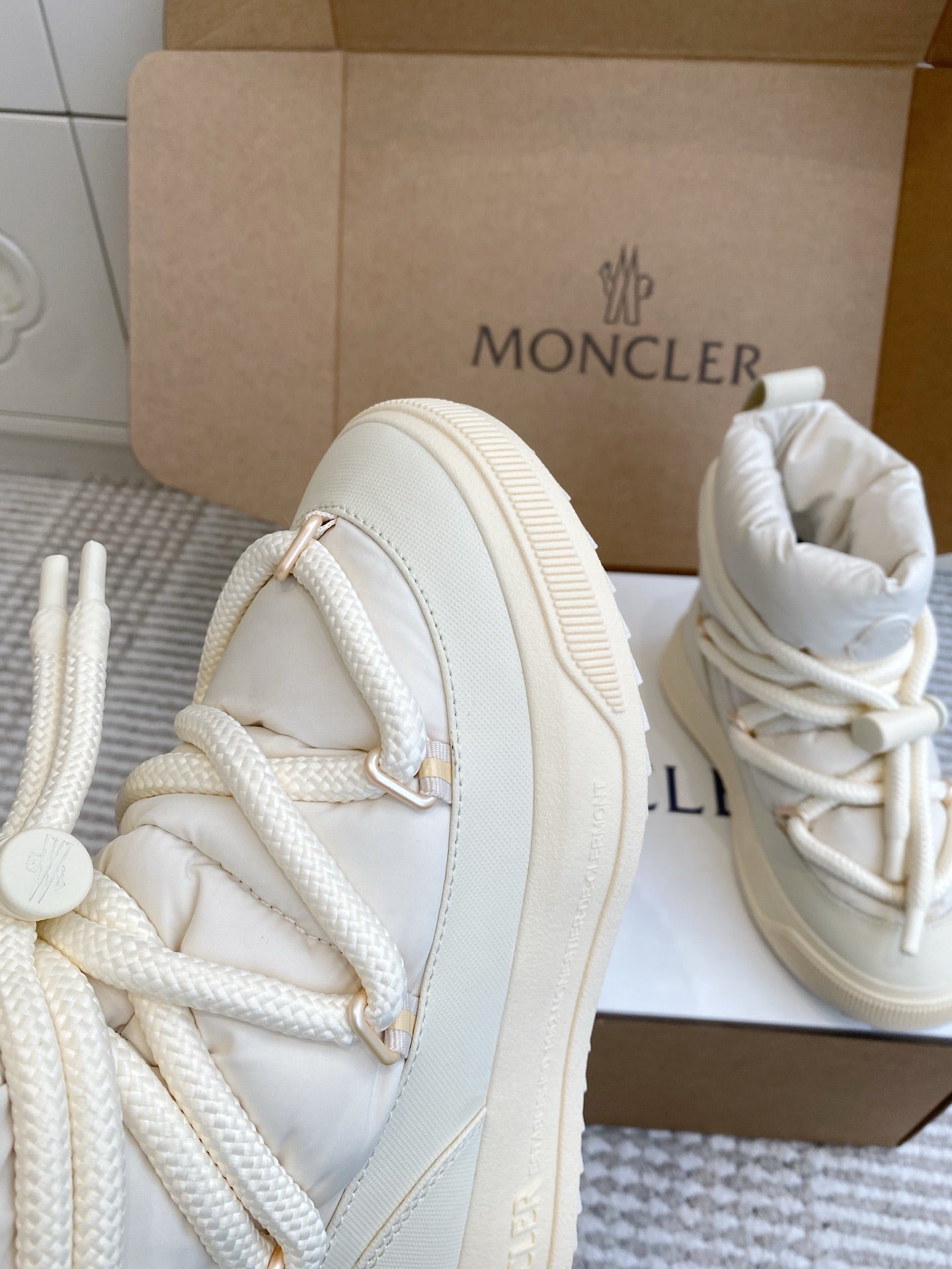 White Moncler high-top sneaker side view with lace-up stitching and thick sole