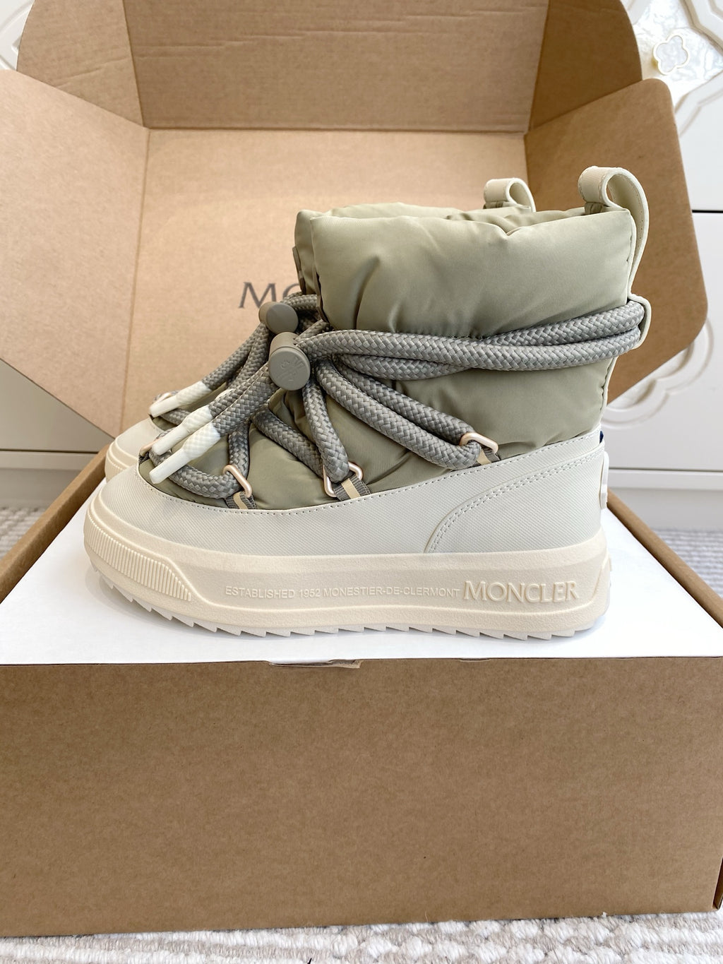 Moncler high-top sneaker with sage green padded collar, gray laces, and white midsole