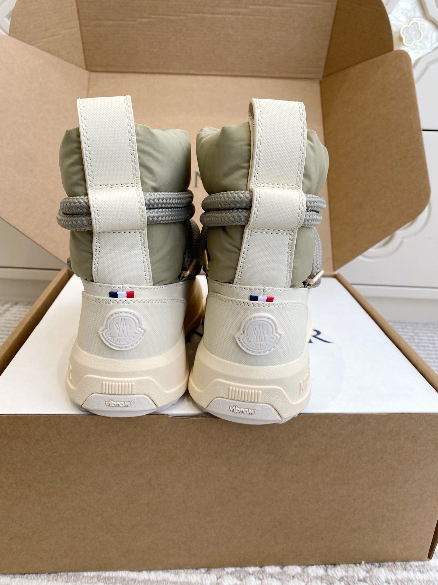 Moncler high-top sneakers with white heel straps, sage green uppers, and gray laces