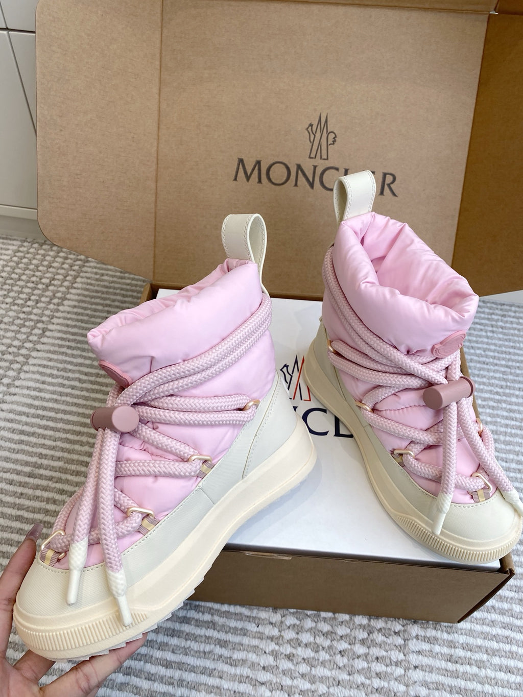 Moncler pink puffer sneakers held up, showing lace-up fronts and thick white soles