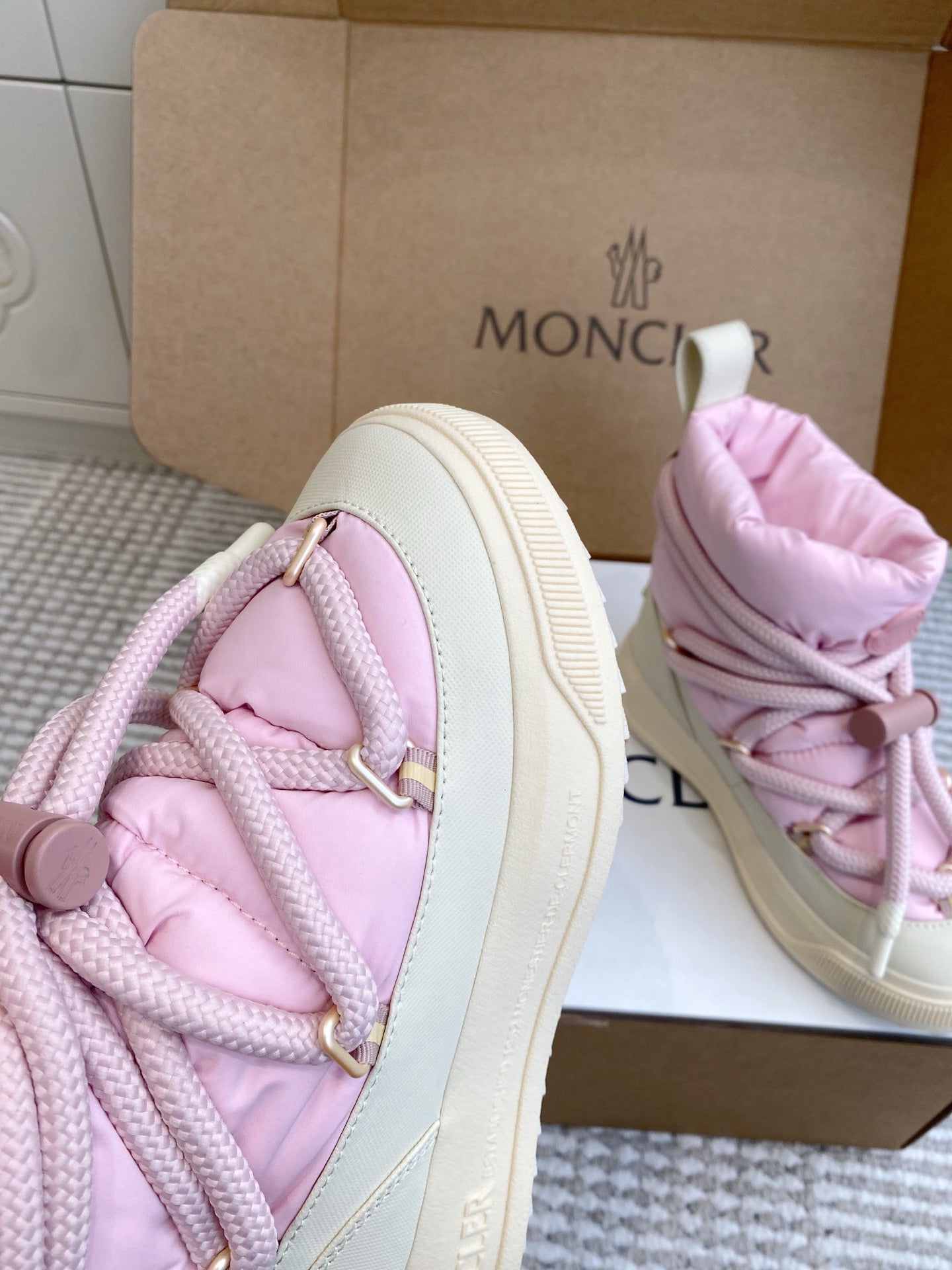 Moncler pink puffer sneaker close-up with laces, gold trim, and side logo
