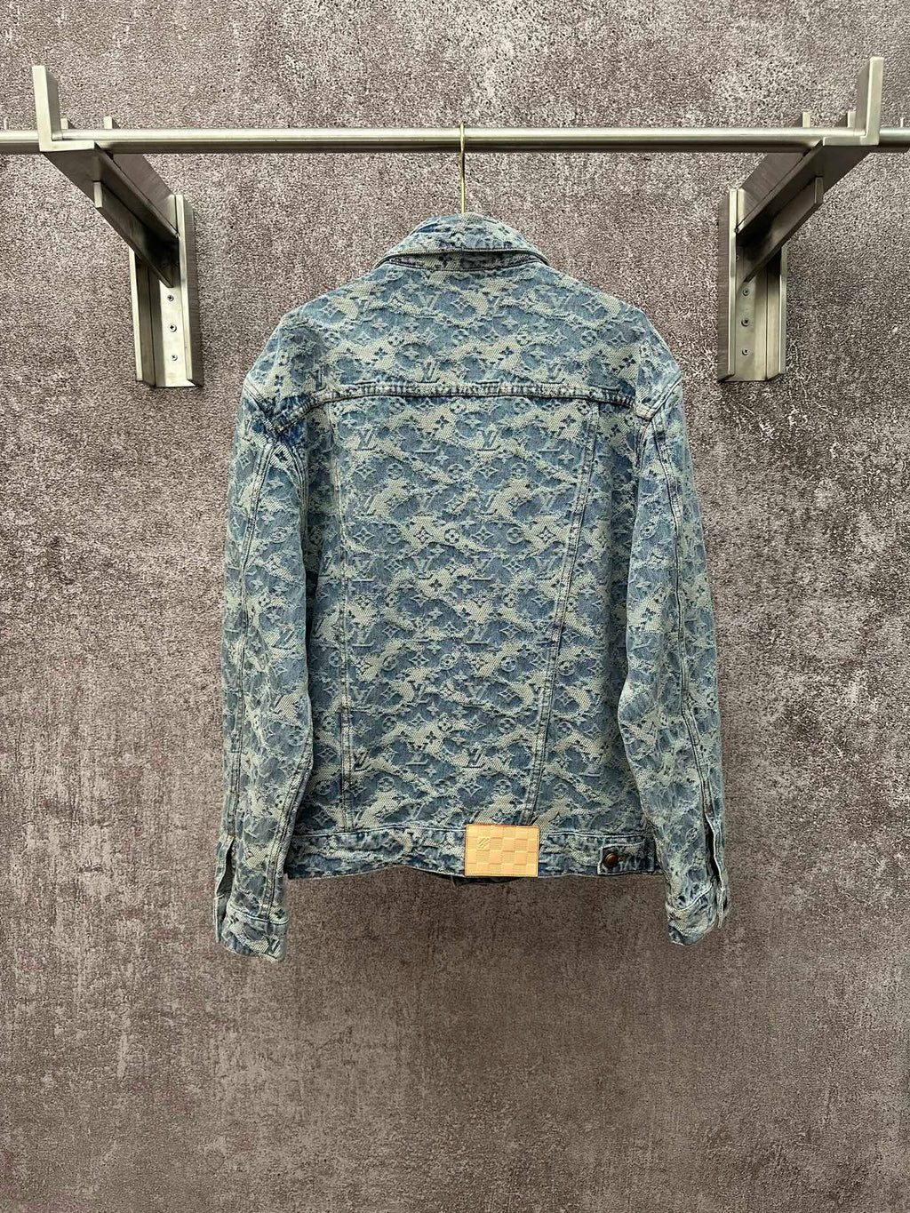 Blue denim jacket with all-over monogram pattern, button back, and waistband detail