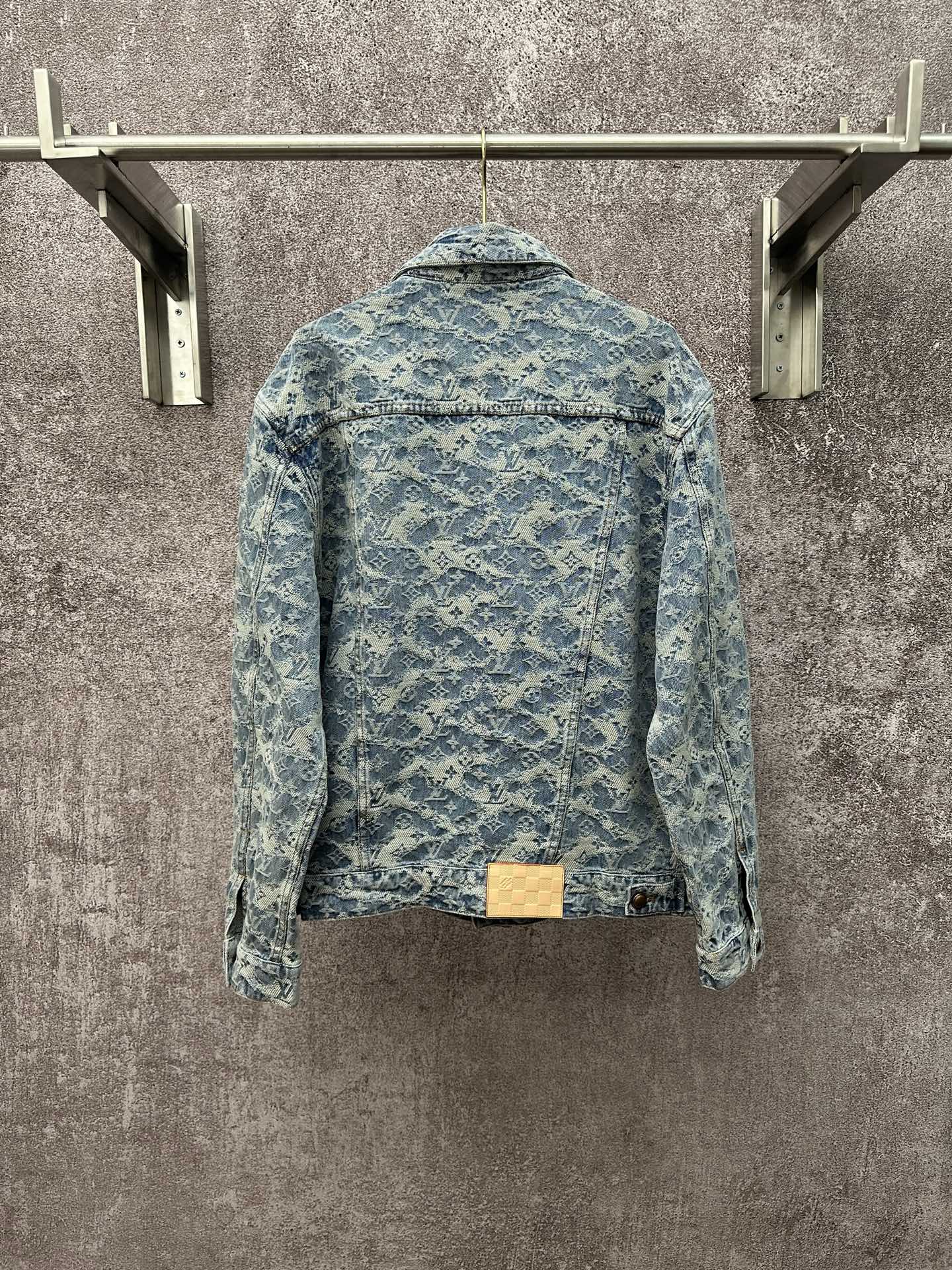 Blue denim jacket with all-over monogram pattern, button back, and waistband detail