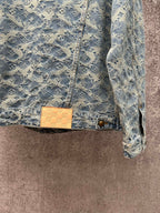 Blue denim jacket with monogram pattern, tan check patch at waist, and gold button