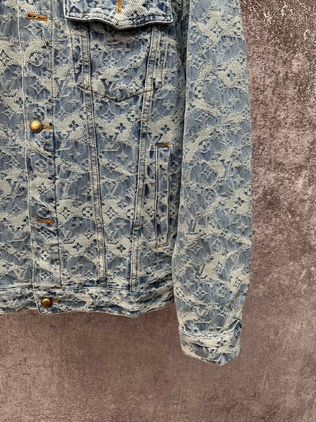 Blue denim jacket with all-over monogram pattern, front flap pockets, and button closure