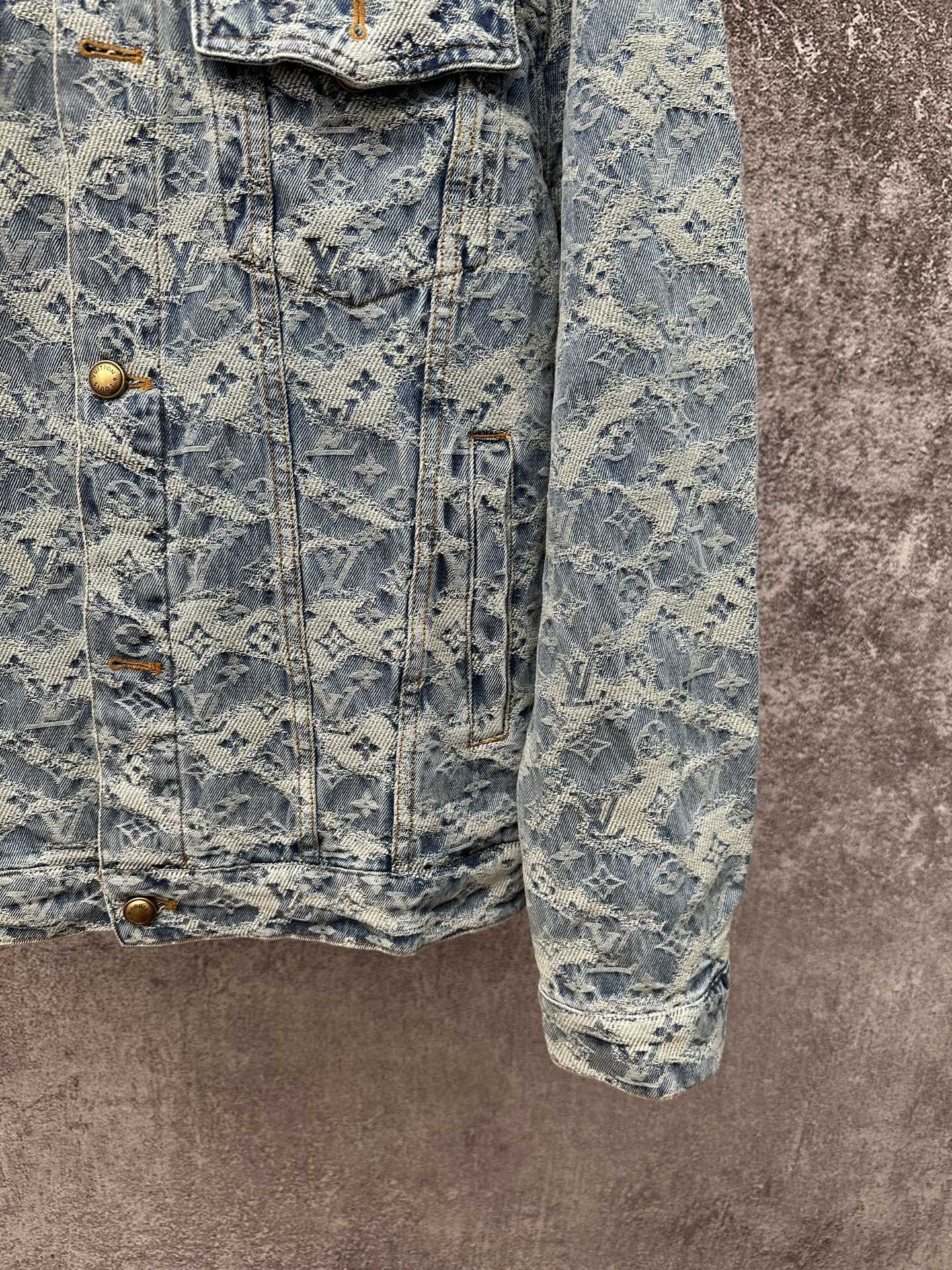 Blue denim jacket with all-over monogram pattern, front flap pockets, and button closure
