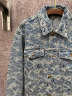 Blue denim jacket close-up with monogram pattern, gold buttons, and flap front pockets