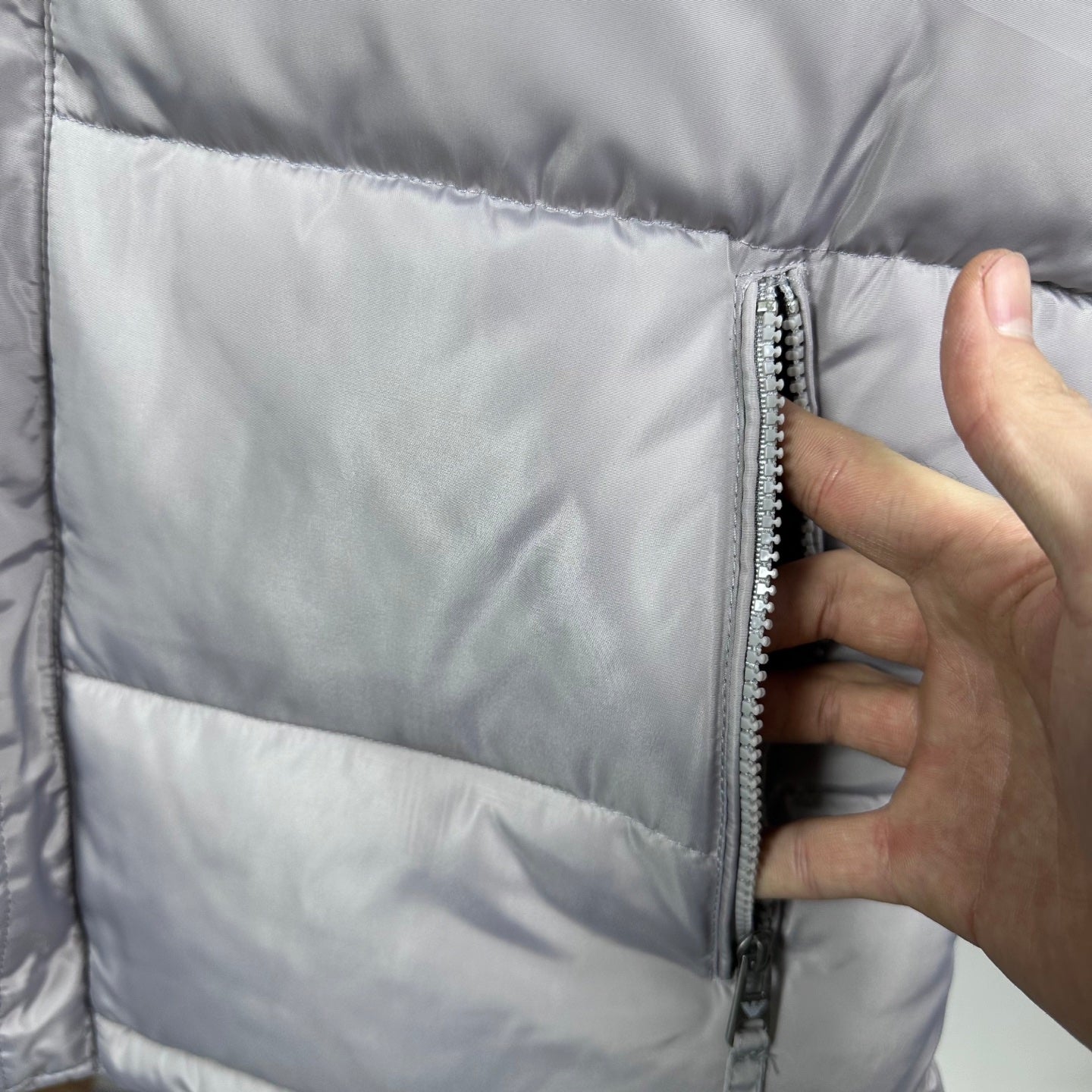 Amiri hooded puffer vest, light gray, close-up of side zipper and quilted panels