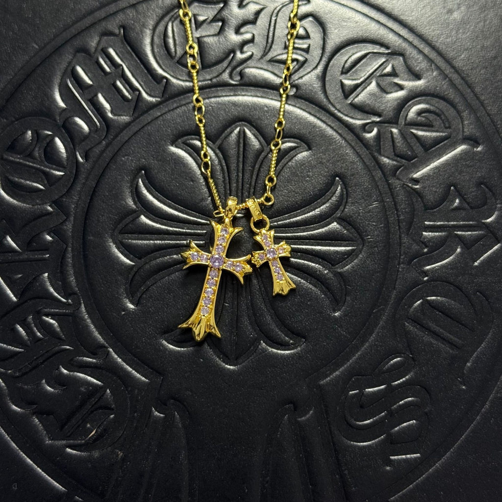 Gold-tone cross pendant necklace with purple gem accents on chain