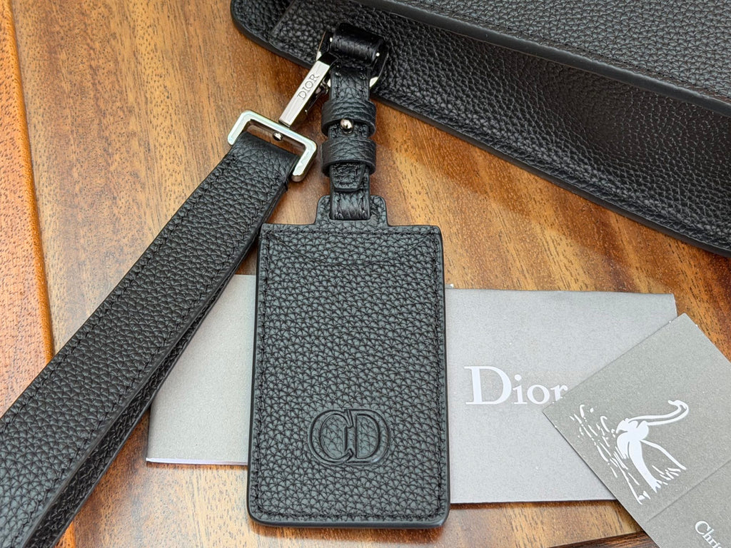 Dior bag leather keychain charm with CD emblem attached to dark strap