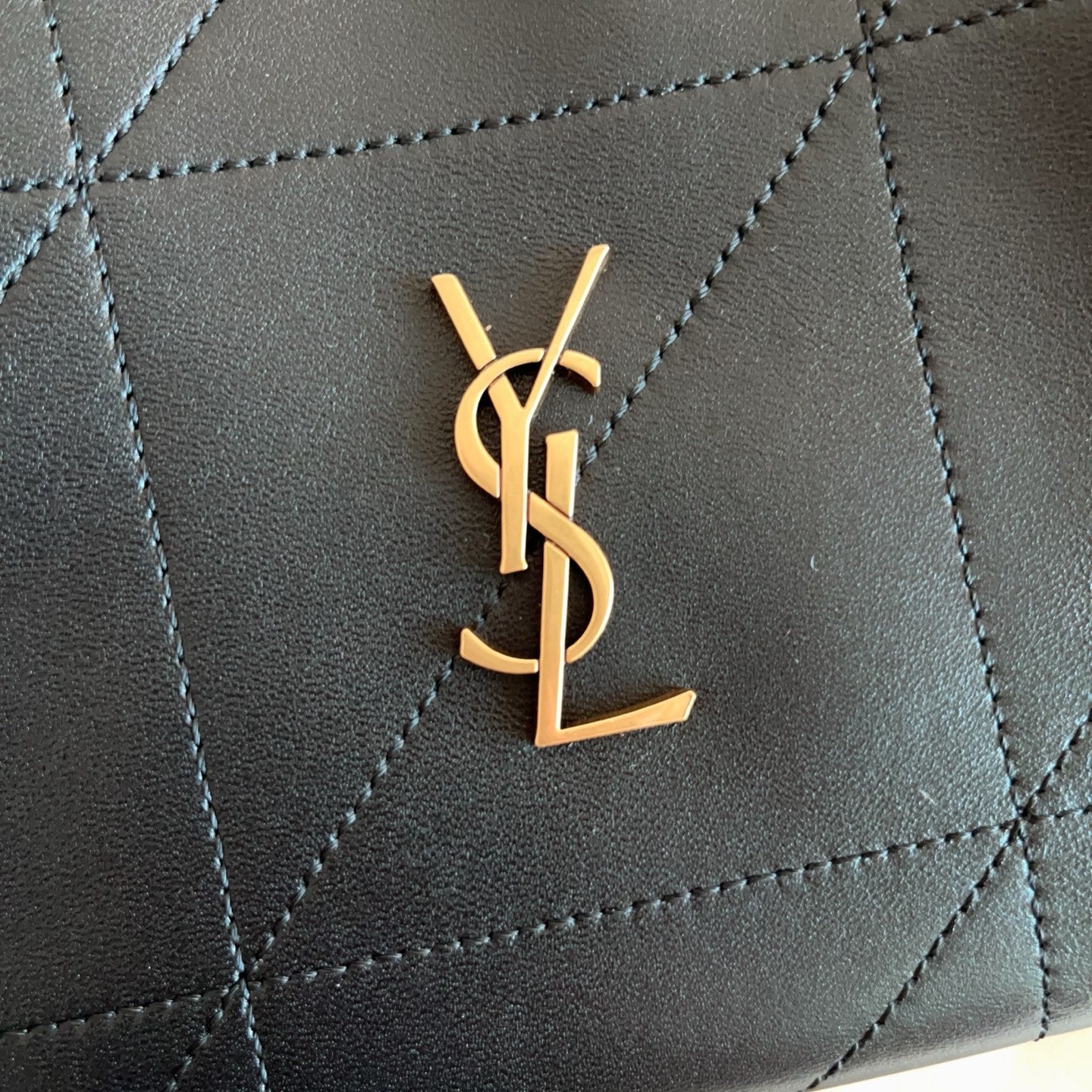 Saint Laurent YSL gold logo plaque on black quilted leather bag front