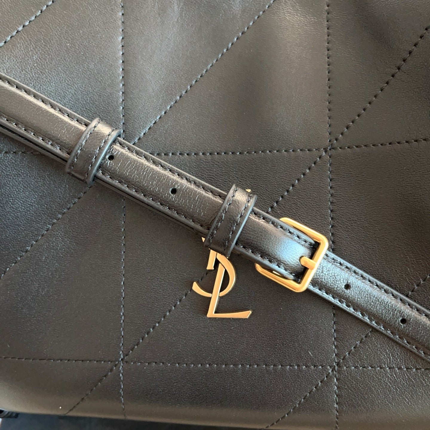 Saint Laurent strap with gold buckle detail on black quilted leather bag