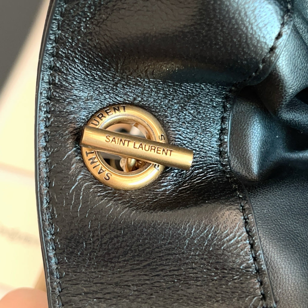 Saint Laurent gold snap-ring hardware with engraved text on black leather