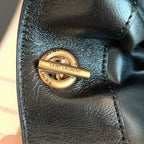 Saint Laurent gold snap-ring hardware with engraved text on black leather