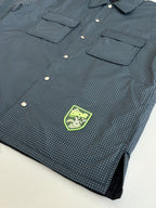 Blue check jacket close-up with logo patch, front buttons, and chest pockets