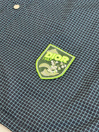 Blue check fabric close-up with green Dior logo shield patch