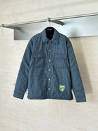 Blue check button-up jacket with long sleeves, flap pockets, and logo patch