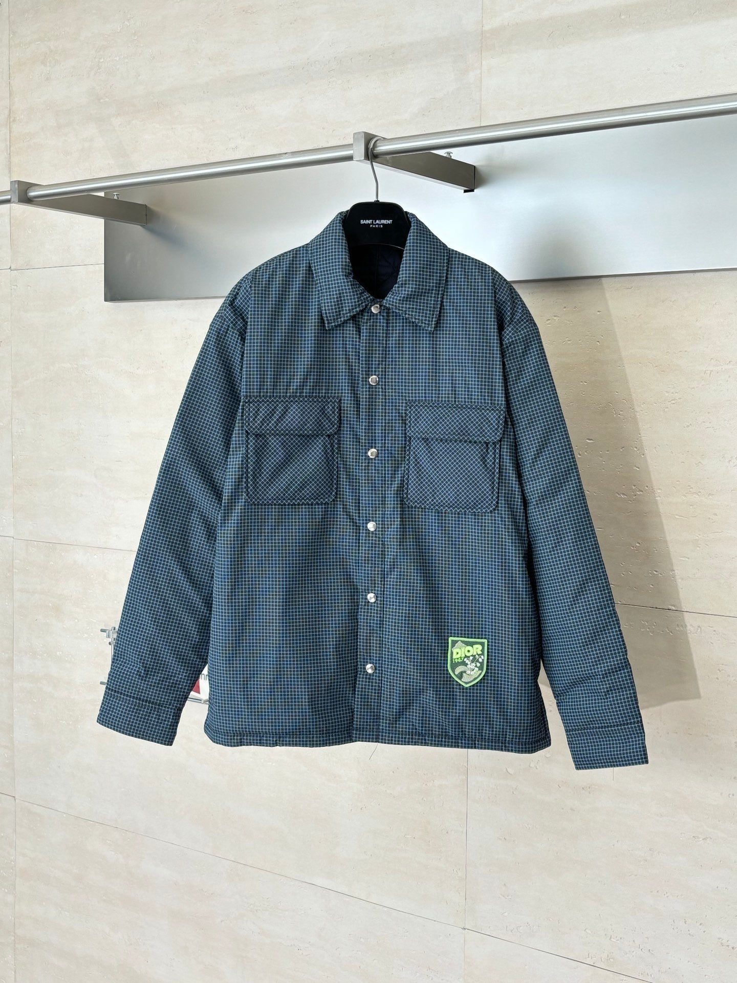 Blue check button-up jacket with long sleeves, flap pockets, and logo patch