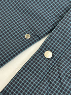 Blue check jacket detail with round button and diagonal seam stitching