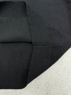 Black sweater cuff with ribbed knit trim at the sleeve hem.