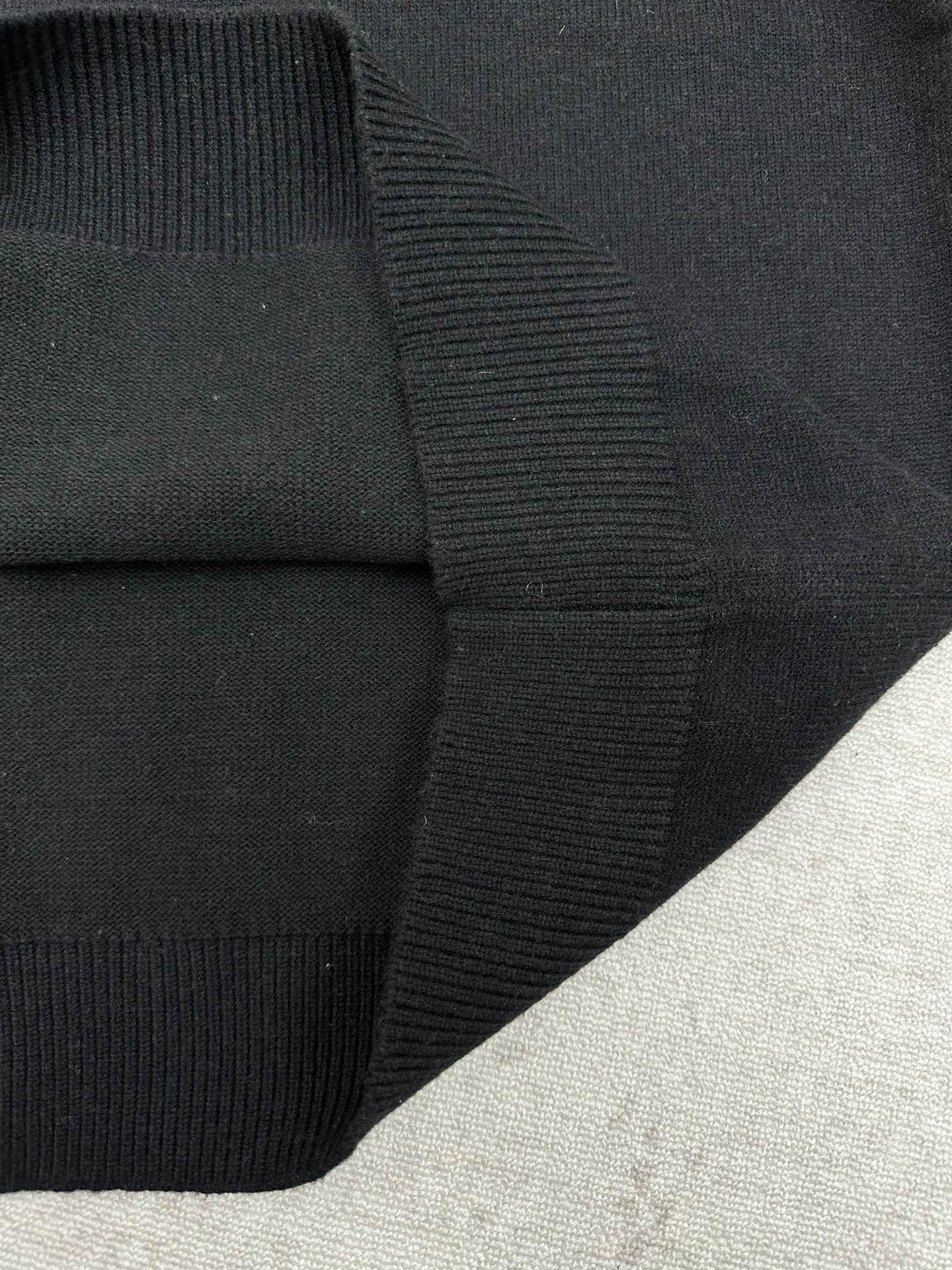 Black sweater cuff with ribbed knit trim at the sleeve hem.