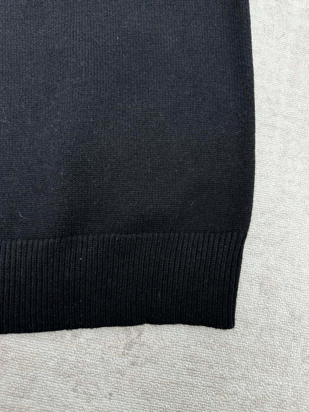 Black sweater hem with ribbed knit edge.